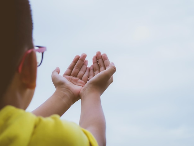 Photo rear view of boy praying against sky