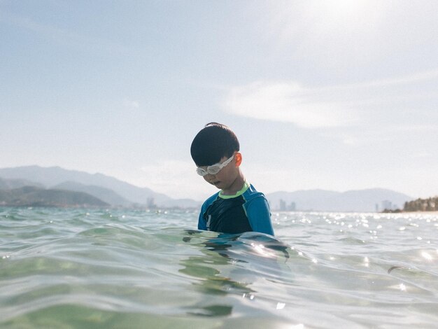 Rear view of boy in sea against sky