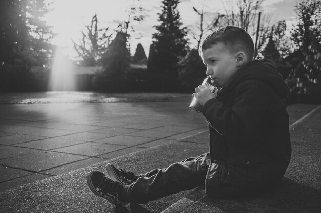 Photo rear view of boy sitting at park