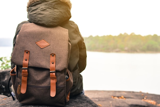 Rear view of boy sitting on rock against lake