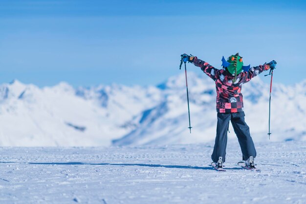 Foto vista posteriore di un ragazzo che scia su una montagna innevata contro il cielo blu