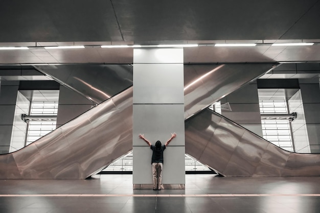 Foto vista posteriore di un ragazzo in piedi contro una colonna architettonica alla stazione della metropolitana