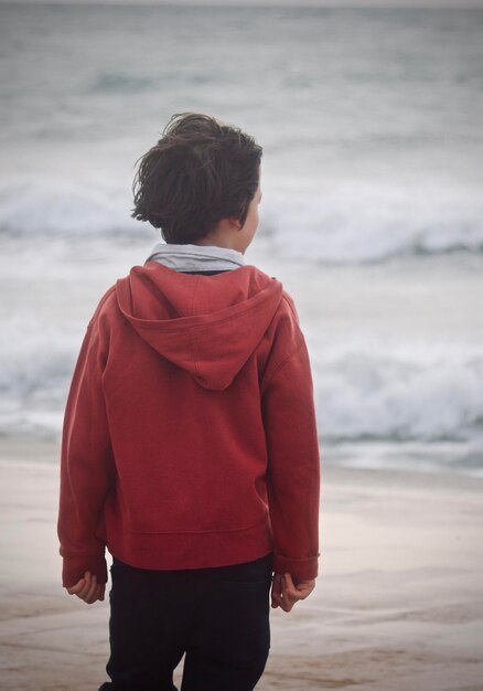 Photo rear view of boy standing against sea