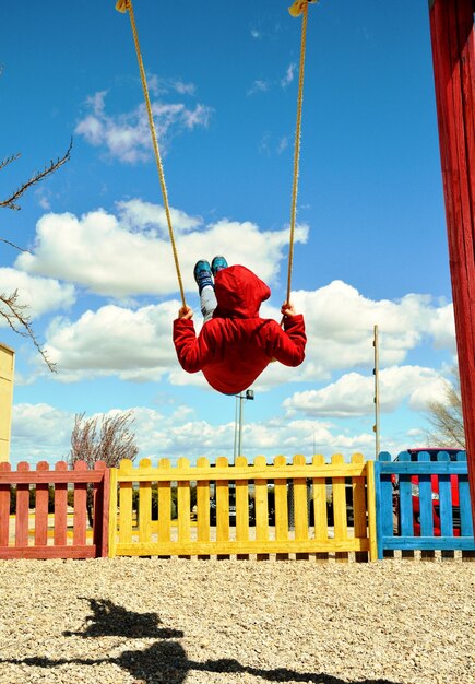 Rear view of boy swinging on swing during sunny day