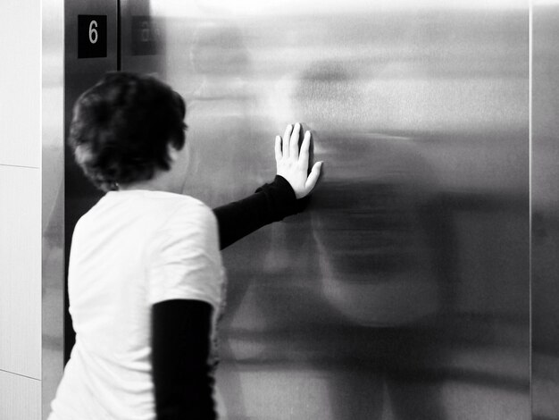 Photo rear view of boy touching elevator door