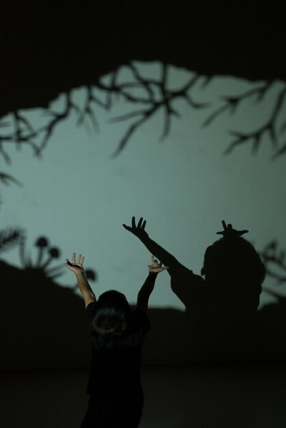 Photo rear view of boy with arms raised standing against wall