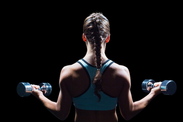 Photo rear view of braided hair woman lifting dumbbells