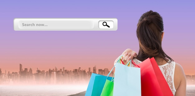 Photo rear view of brunette holding shopping bags against city on the horizon