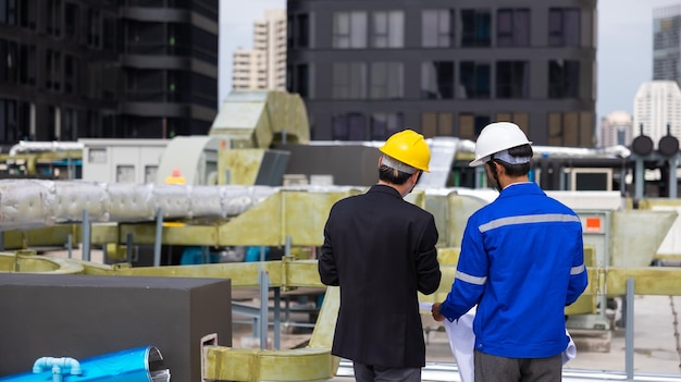 Rear view of business man and office building owner and energy\
engineer plan a project to build a solar panel for the building\
under construction clean and green alternative energy concept