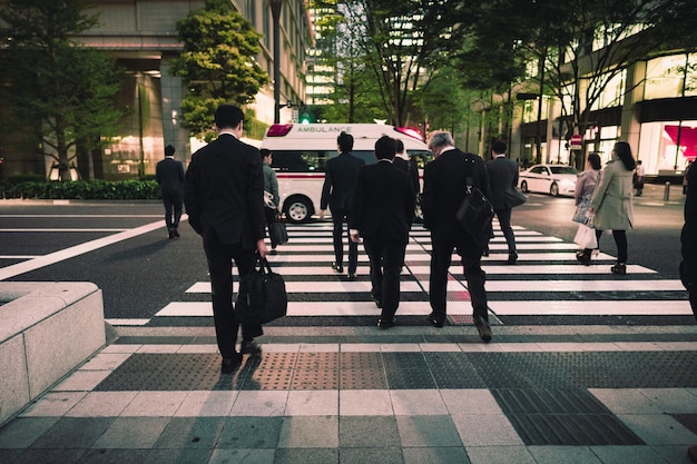 街を横断するビジネスマンたちの後ろの景色