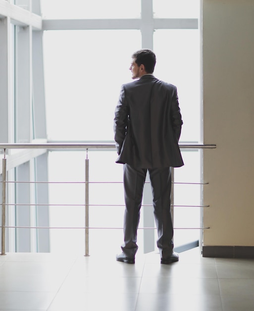 Rear view businessman standing in the lobby of a modern office