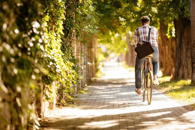 自転車で仕事に行くカジュアルなビジネスマンの背面図。