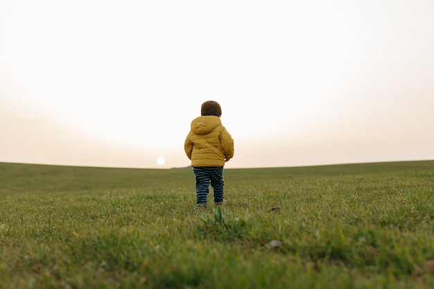 사진 잔디 에 노란색 재 을 입은 아이 의 뒷면