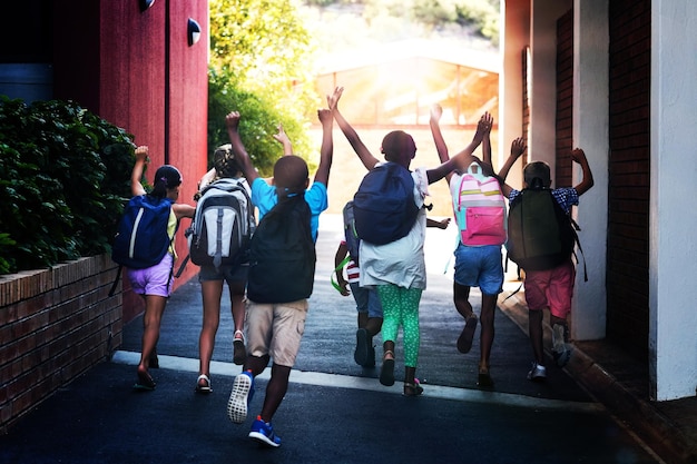 Rear view of classmates running at school campus