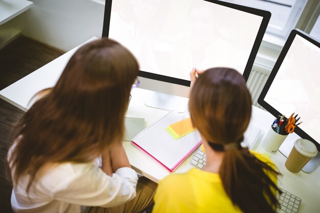 Foto retrovisione dei colleghi che lavorano allo schermo di computer all'ufficio creativo