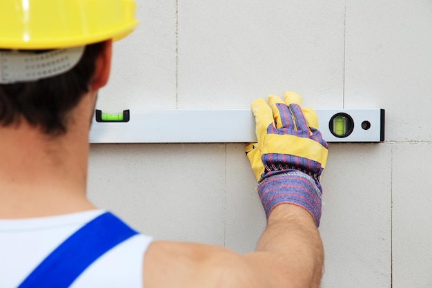 Rear view of construction worker measuring on wall