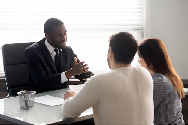 Rear view couple during meeting with african ethnicity family\
lawyer spouses and realtor negotiating about rental property banker\
worker consulting first realestate purchasing lease mortgage\
concept