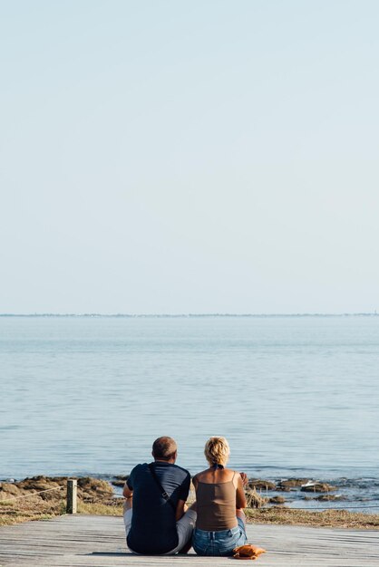 Rear view of couple looking at sea against clear sky