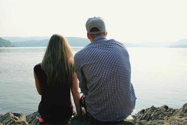 Photo rear view of couple sitting against sea