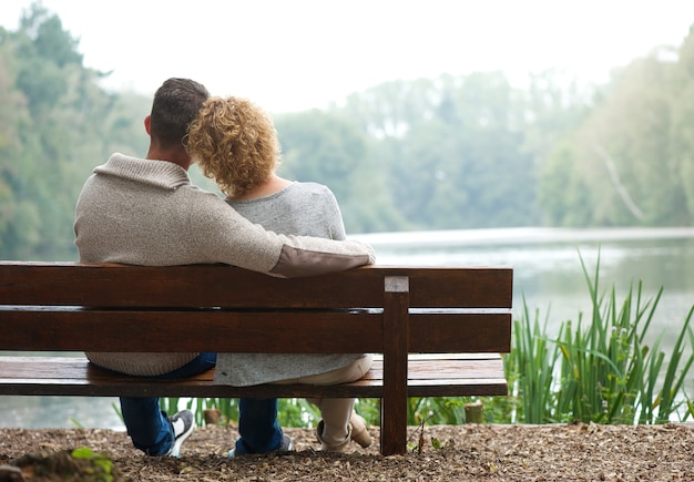 Rear view couple sitting on bench outdoors