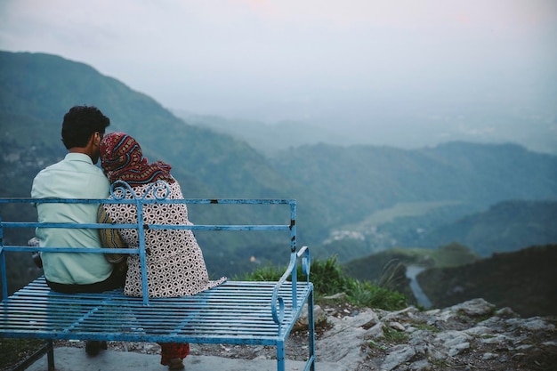 rear view of couple sitting on seat against mountains