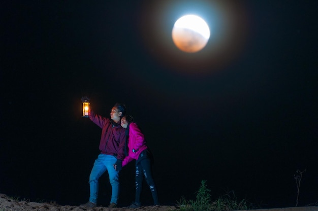 Foto vista posteriore di una coppia in piedi contro le luci illuminate di notte