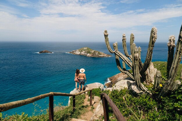 Rear view of couple standing by sea on rock