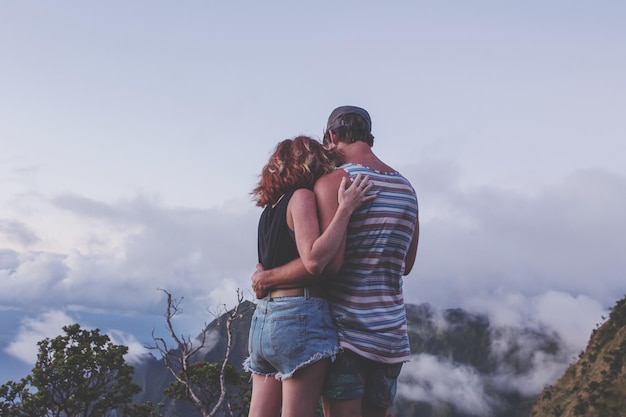 Photo rear view of couple standing on mountain against sky