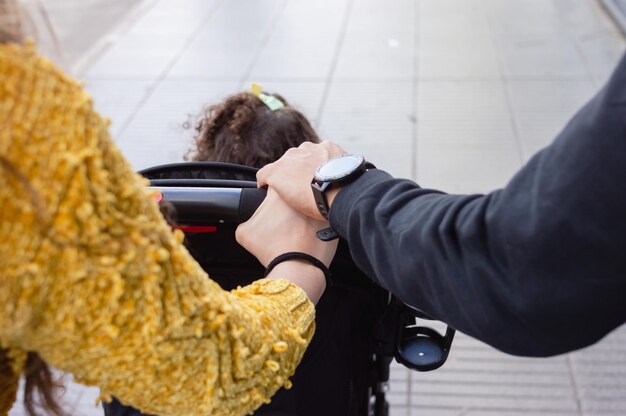 rear view of couple in the street holding hands walking with the baby stroller