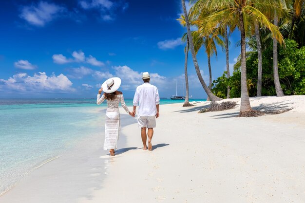 Rear view of couple walking on beach against sky