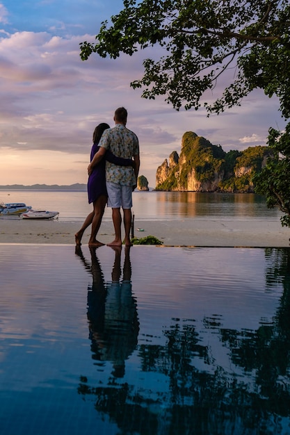 Rear view of couple walking at beach against sky