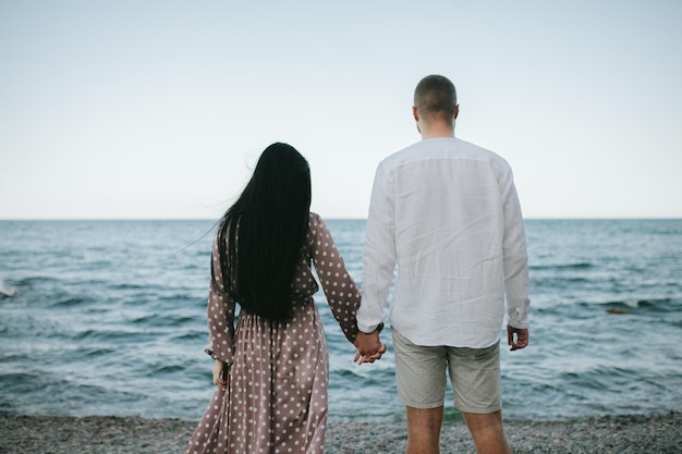 Rear view of a couple walking on the beach holding hands