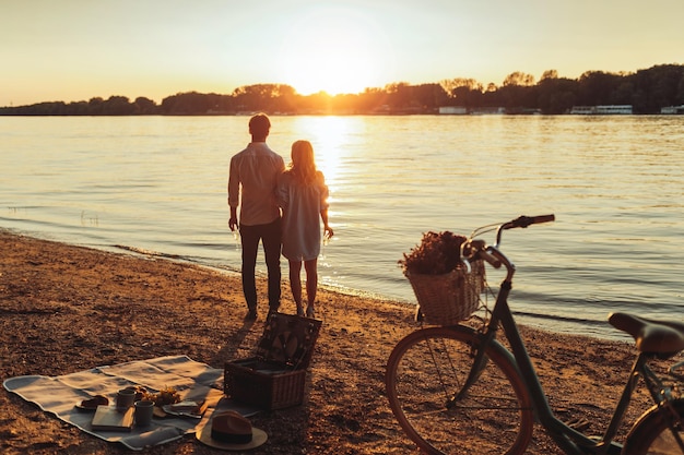 Rear view of a couple watching the sunset next to the river