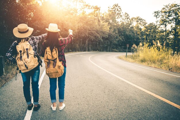 バックパックを背負ったカップルが道路に立っている後ろの景色