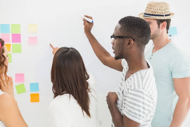 Rear view of coworkers writing on sticky notes