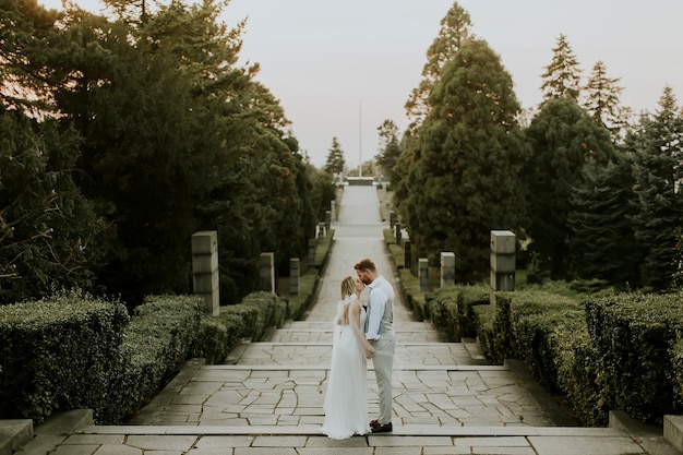 Photo rear view of the cute young newlywed couple walking on stairs in the park