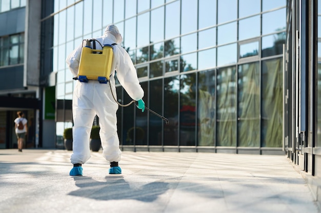 Rear view of disinfection worker spraying city streets in order to prevent the spread of COVID19