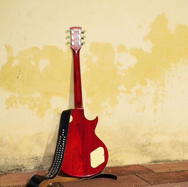 Rear view of an electric guitar leaned on a rustic wall