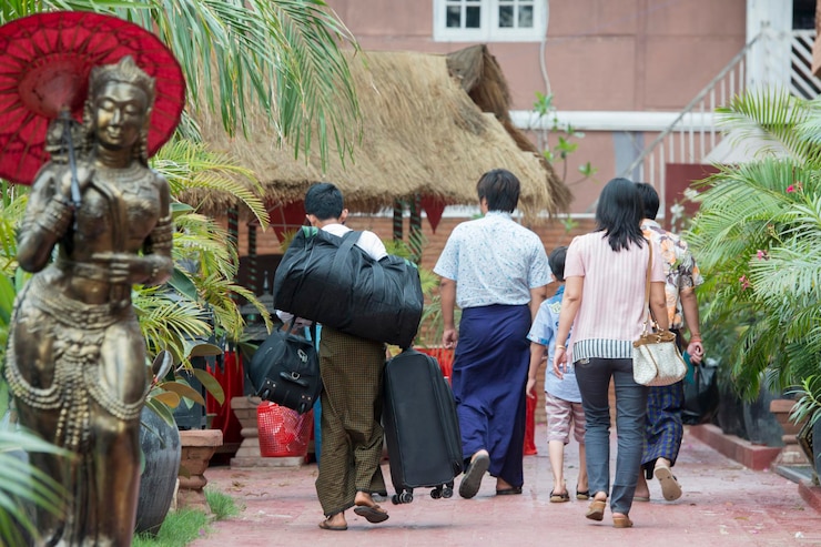 Photo rear view of family carrying luggage while walking on footpath