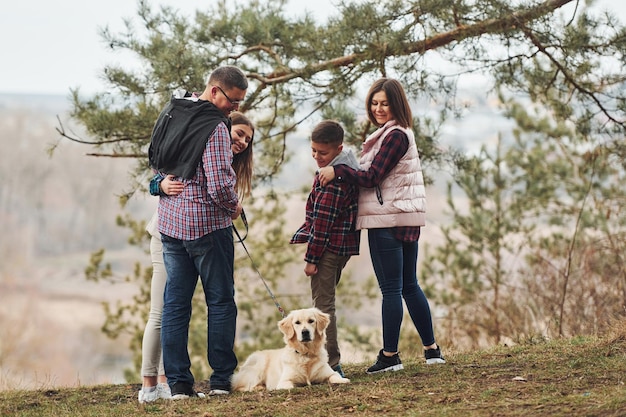 Rear view of family that standing together with their dog outdoors in forest