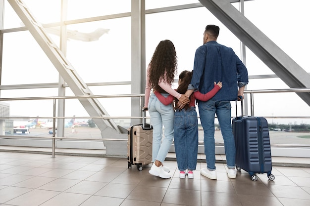 Vista posteriore della famiglia con la figlia che guarda fuori dalla finestra all'aeroporto