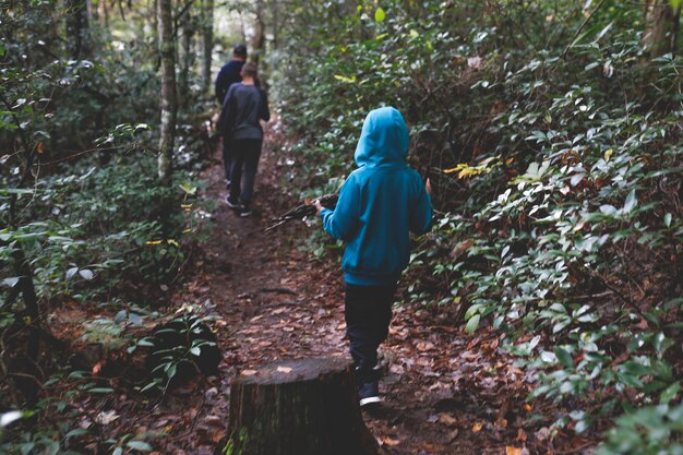 Photo rear view of father and sons walking in forest