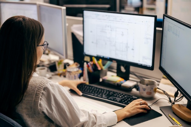 Foto la vista posteriore di un'architetto donna che lavora ai progetti in ufficio.