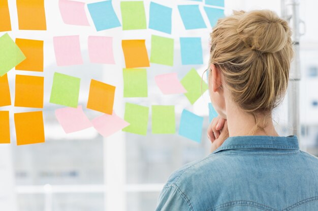 Rear view of a female artist looking at colorful sticky notes