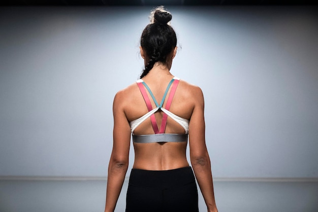 rear view of female athlete standing against wall in gym