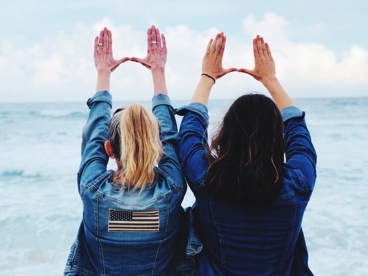 Photo rear view of female friends gesturing at beach