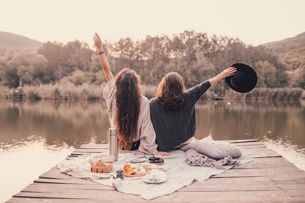 rear view of female friends sitting on pier