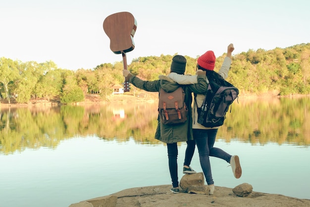 Photo rear view of female friends standing by lake against sky