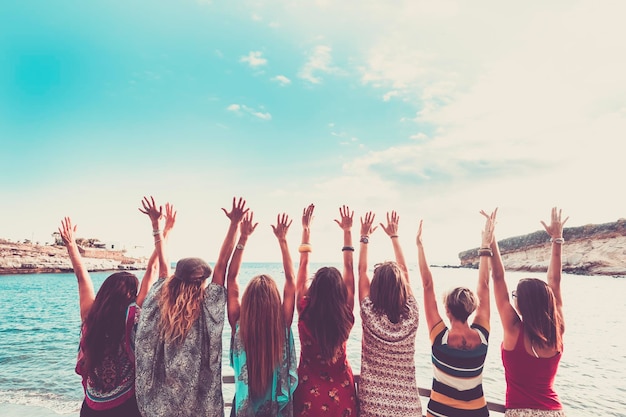 Foto vista posteriore di amiche con le braccia alzate sulla spiaggia