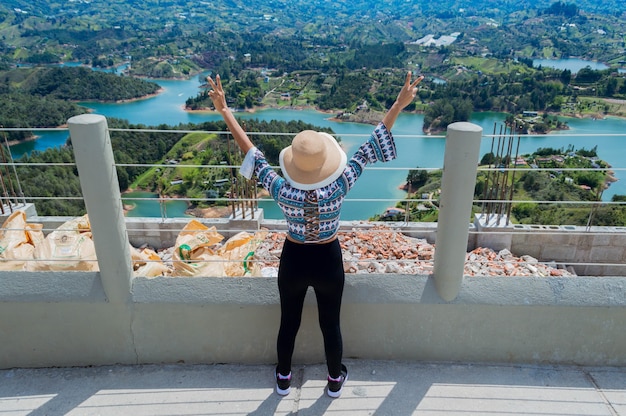 Foto vista posteriore del turista femminile alzando le mani in corrispondenza del bordo della pietra penol in guatape colombia